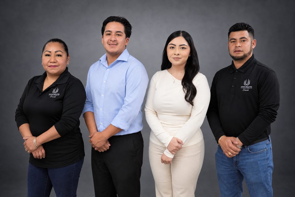 Four team members stand in a row: a woman and a man in black UFG Coach polos, a man in light blue and a woman in cream