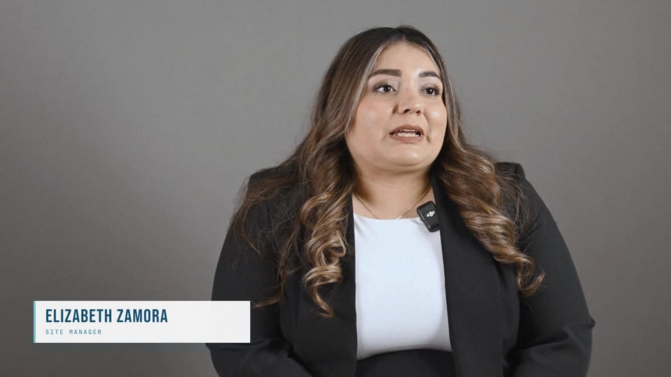 Elizabeth Zamora speaking in a black blazer over a white top, a frame from the film No Dust