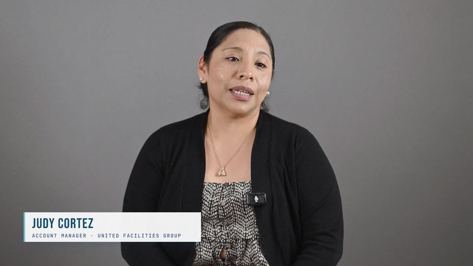 Judith Cortes speaking in a black cardigan over a patterned top, a frame from the film Growth Through Teamwork